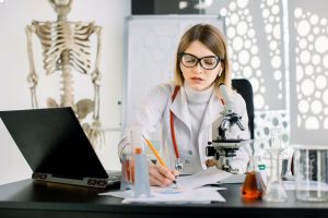 Young attractive Caucasian woman scientist in white coat and eyeglasses in the scientific medical